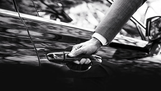 Driver with his hand on the car door handle.